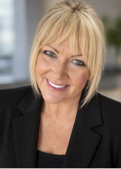 CLAIRE EVANS-BELL: head-and-shoulders portrait of smiling woman with blonde bob in black blazer, blurred background